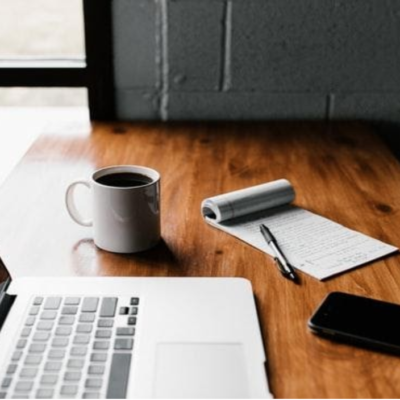 Desk with coffee, pen, phone and laptop