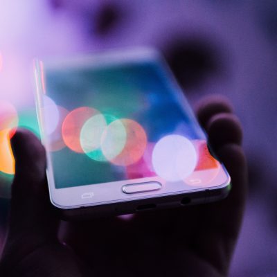 Hand holding phone with bright lights reflected on screen