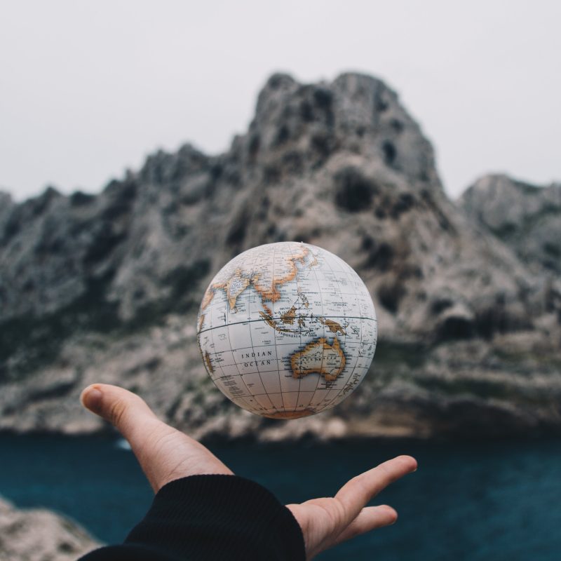 Hand hold small globe in front of mountain