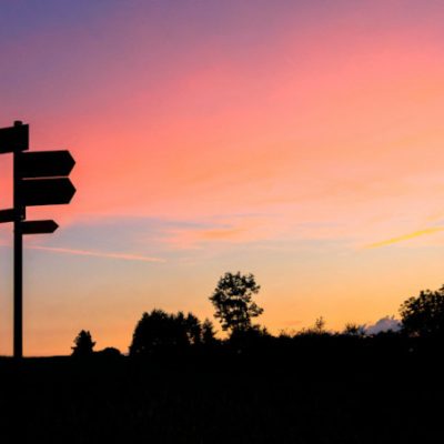 signpost silhouetted against a sunset